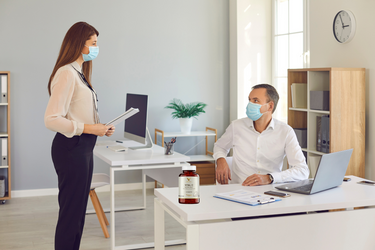 Współpracownicy w biurze noszący maski z powodu syncytialnego wirusa oddechowego