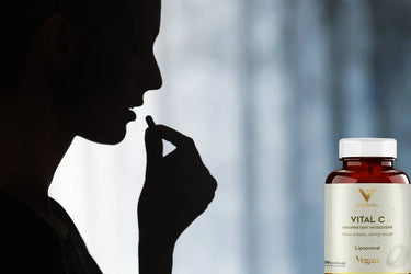 Kobieta przyjmująca kapsułkę liposomalnej witaminy C i butelka Vital C
