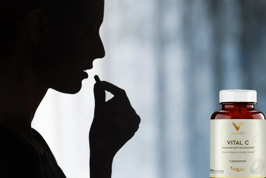 Kobieta przyjmująca kapsułkę liposomalnej witaminy C i butelka Vital C